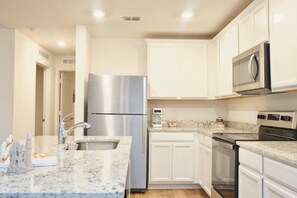 A modern kitchen with white cabinets, stainless steel appliances, and a granite countertop. - Family Paradise Palm Coast Fire Pit Playground (Palm Coast)