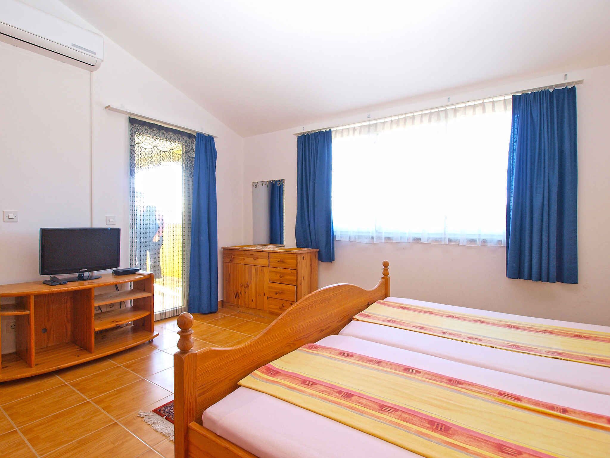 Ein Schlafzimmer mit einem Bett, einem Fernseher, einer Kommode und einem Fenster mit Vorhängen.