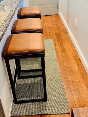 Drie houten krukken met metalen poten en een geweven zitting, staand op een houten vloer.