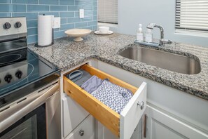 Eine Küche mit Granit-Arbeitsplatte, Edelstahl-Spüle und einer Holzkasten-Einheit.