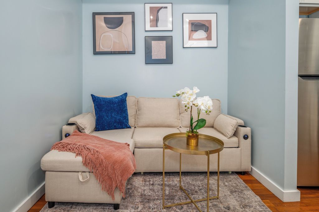 A living room with a sofa, a coffee table, and a rug. There are framed pictures on the wall.