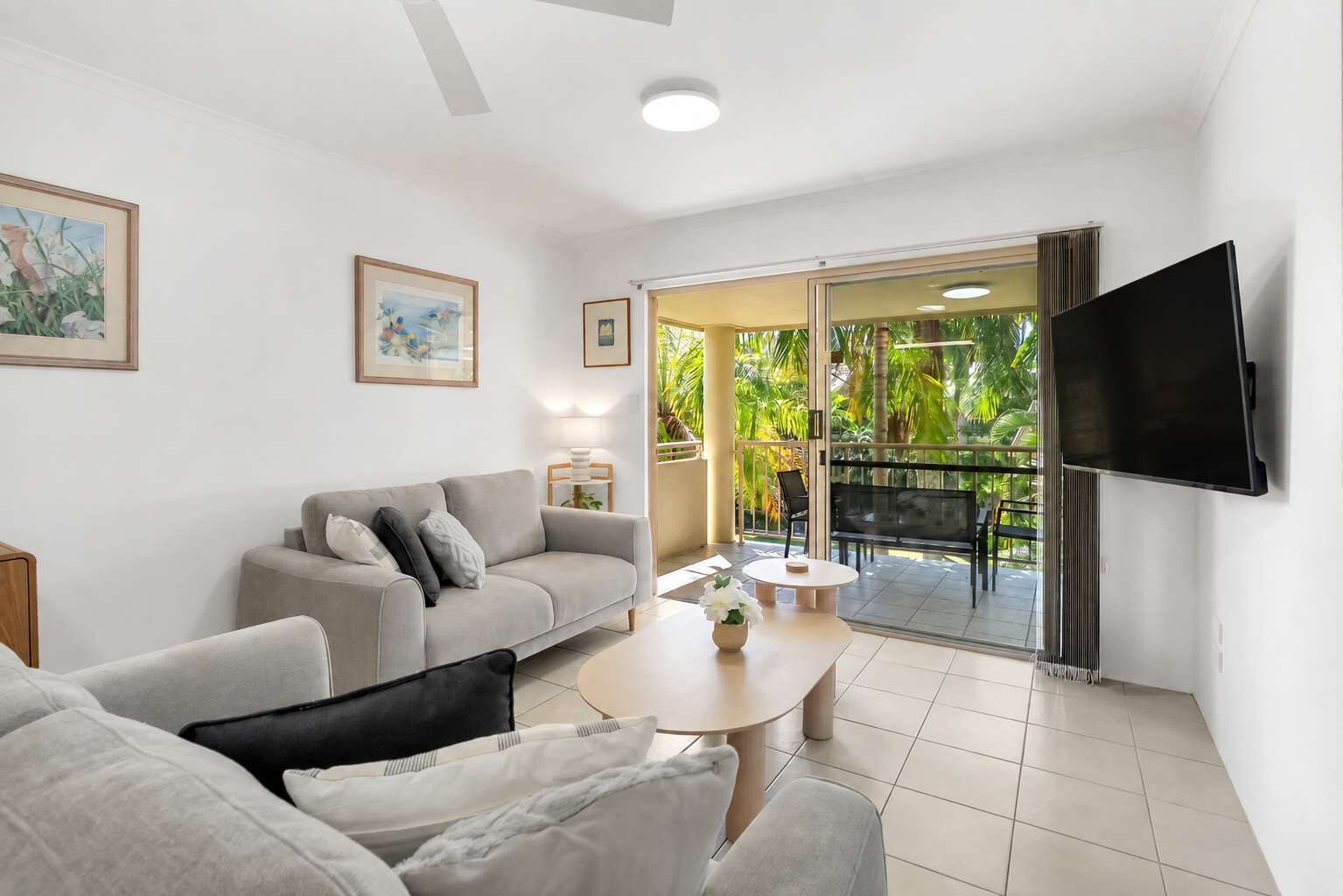 A modern living room with a sofa, a coffee table, and a TV mounted on the wall.