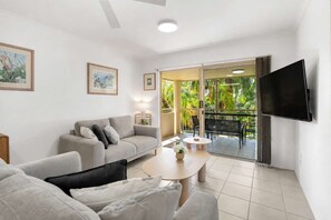 Ein modernes Wohnzimmer mit einer Couch, einem Couchtisch und einem an der Wand befestigten Fernseher.