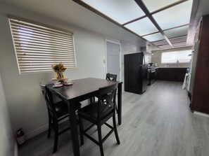 A modern kitchen with a built-in refrigerator, a dining area with a table and chairs, and a window with blinds. - Spacious House near Disney/Knott's (La Mirada)