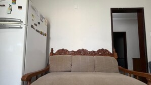Una habitación con cama, cabecera de madera, refrigerador blanco y una puerta.