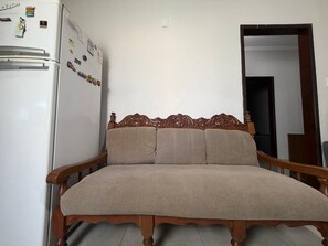 Een kamer met een bed, een houten hoofdbord, een witte koelkast en een deur.