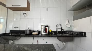 Cozinha com bancada de granito, pia de aço inoxidável e forno embutido.