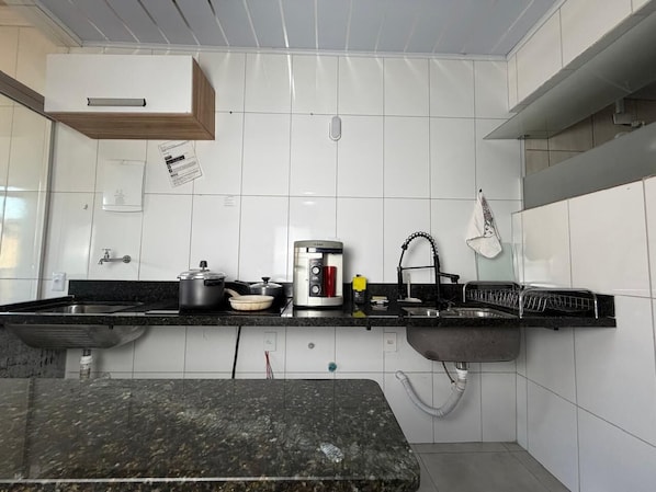 A kitchen with a granite countertop, stainless steel sink, and a built-in oven.