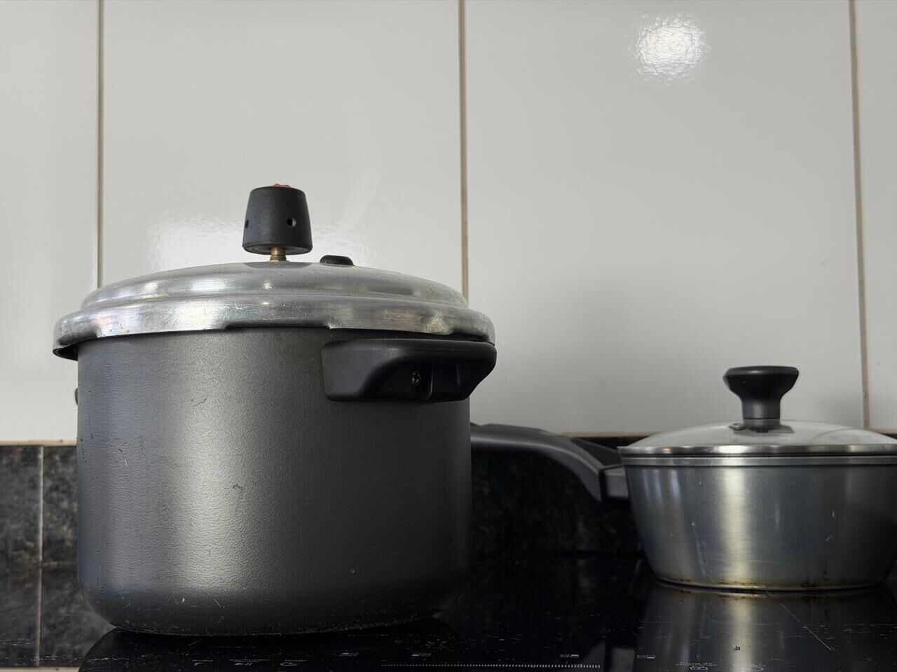Una cucina con una pentola grande e una più piccola su un piano di lavoro nero.
