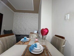 A dining table set with plates, cups, and a heart-shaped balloon.