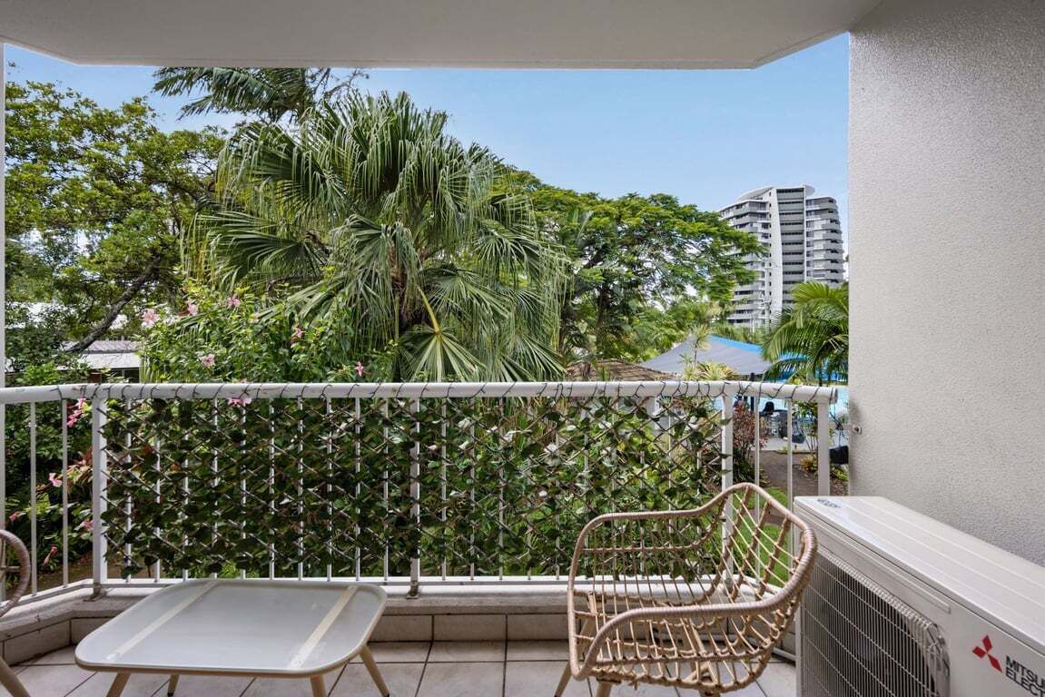 A balcony with a white metal chair, a small table, and a white railing.