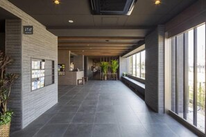 A hallway with a reception desk, a seating area, and large windows. - (Fukuoka)