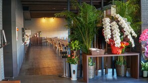 A hotel lobby with a reception desk, a long row of chairs, and various potted plants. - (Fukuoka)