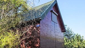 Um edifício térreo com telhado inclinado, uma janela visível e uma porta pequena.