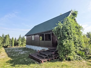 A single-story wooden cabin with a sloped roof, a porch with wooden steps, and a small garden area with potted plants. - Oaza spokoju by Interhome (Borszowice)
