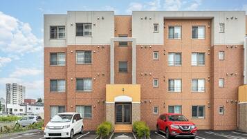 Un edificio de apartamentos de varios pisos con un estacionamiento al frente.