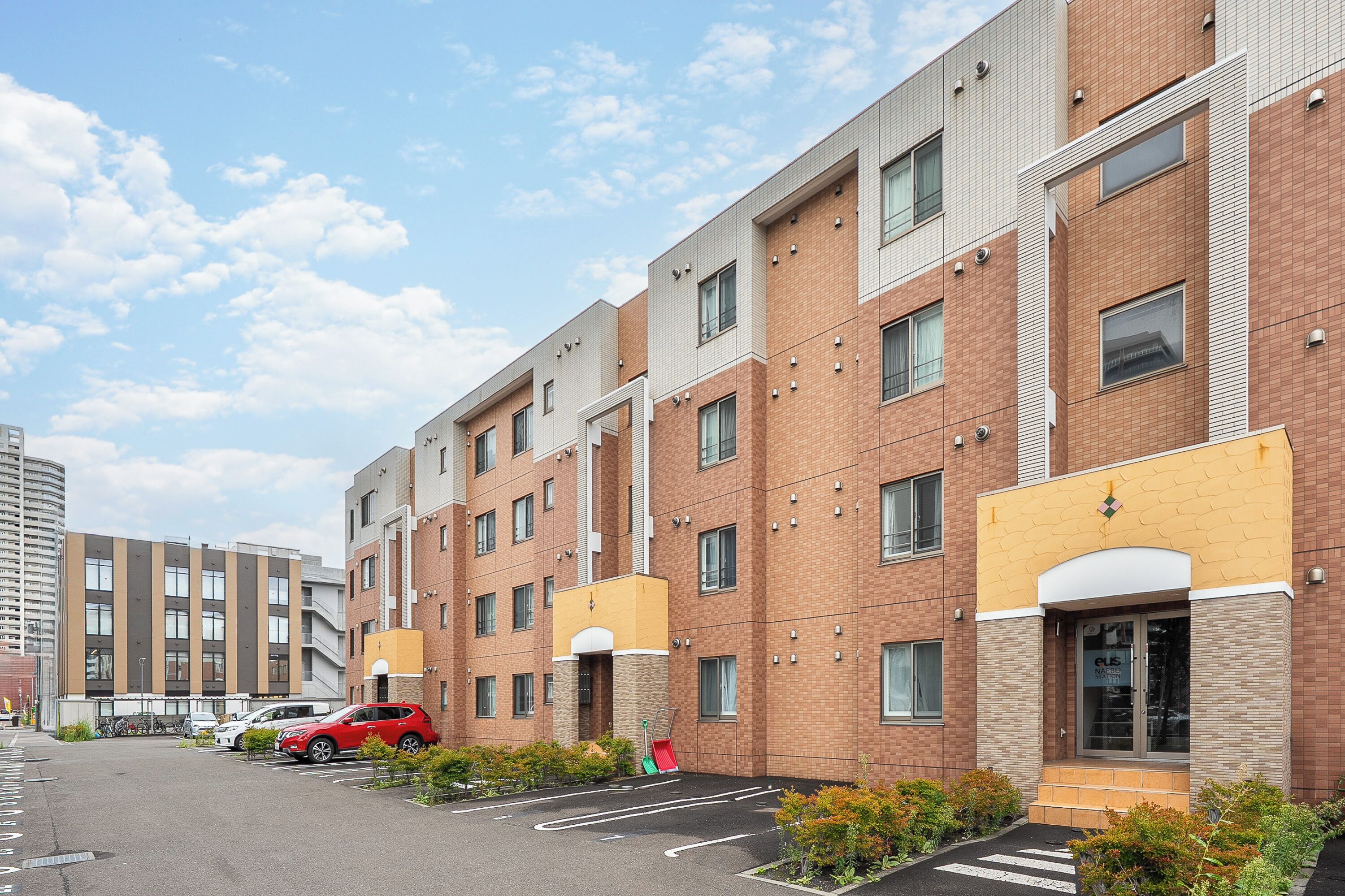A multi-story residential building with a parking lot in front.