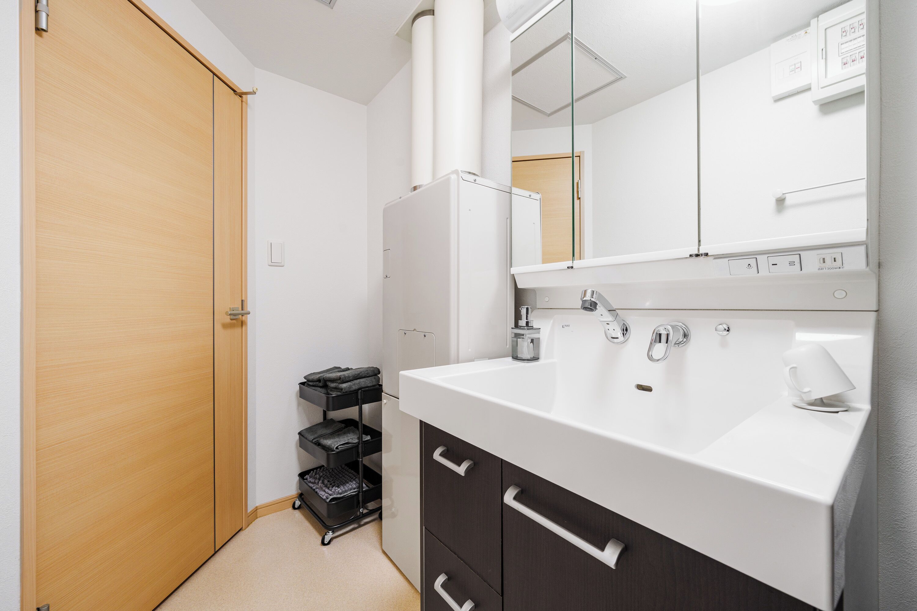 A bathroom with a white sink, a mirror, a towel rack, and a door.