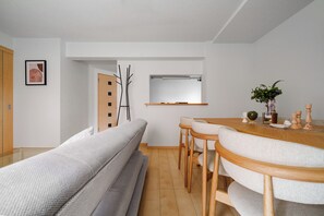 A modern, minimalist living space with a sofa, dining table, and chairs. - E-US NAEBO STATION 101 (Sapporo)