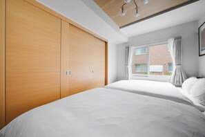Un dormitorio con un armario grande, una cama y una ventana con cortinas.