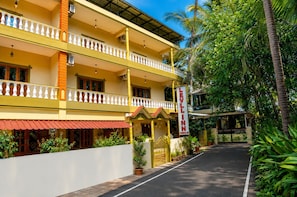 Un hotel con fachada amarilla, varios balcones y un toldo rojo.