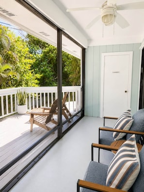 A balcony with a white railing, a wooden chair, a sofa with striped cushions, and a door labeled 'Laundry'.