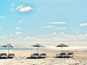 A beach with sun loungers and umbrellas. - Palmetto Place | Beach, Pool & Walkable Dining (Vero Beach)