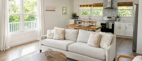A modern living room with a sofa, a coffee table, and a kitchen in the background.