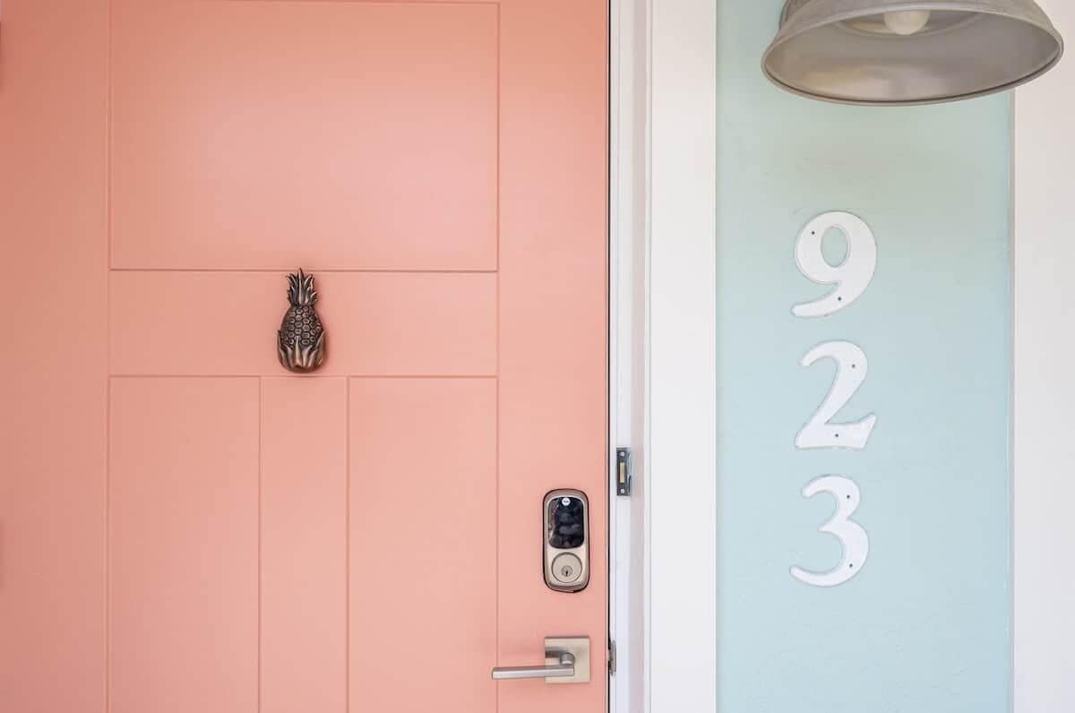 Una puerta con un ojo de cerradura y un timbre, y una pared con los números 9, 2, 3.