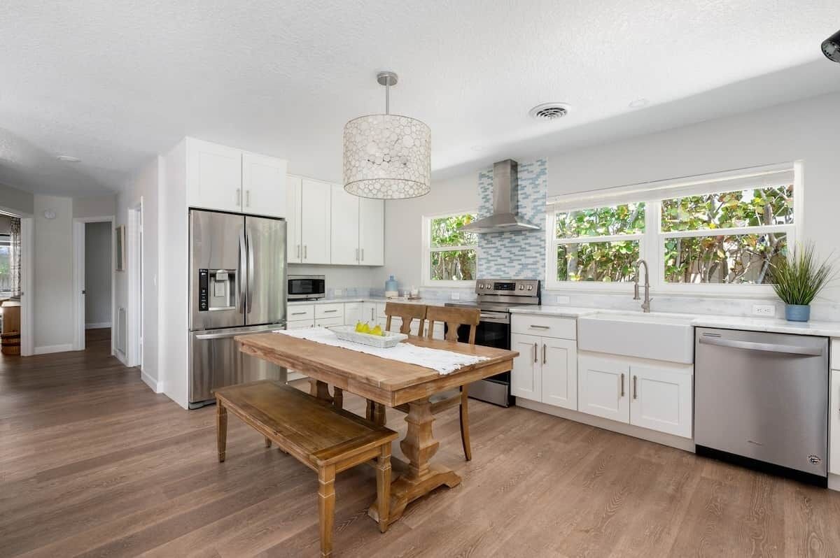 Una cocina moderna con muebles blancos, electrodomésticos de acero inoxidable y una mesa de comedor de madera.