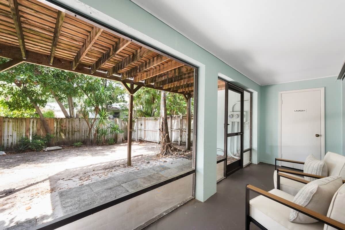 Une pièce donnant sur un jardin, avec une pergola en bois et une porte menant à l’extérieur.