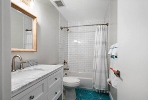 Un baño con lavamanos de mármol, inodoro blanco y bañera.
