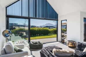 Un salon moderne doté d’une grande porte-fenêtre coulissante donnant sur un balcon avec vue sur les montagnes.