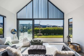 A modern living room with a large sliding glass door leading to a private outdoor area, furnished with a sofa, ottoman, and a globe decoration.