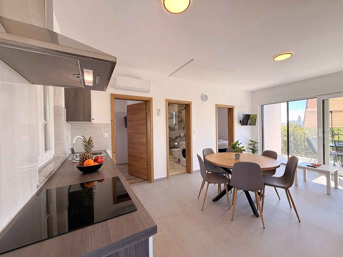 A modern kitchen with a black countertop, a dining area with a round table and chairs, and a large window with a view.