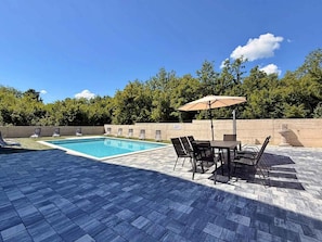 A swimming pool with a tiled deck, outdoor seating, and a view of trees. - Holiday apartment with shared use of pool (Polje/Krk)