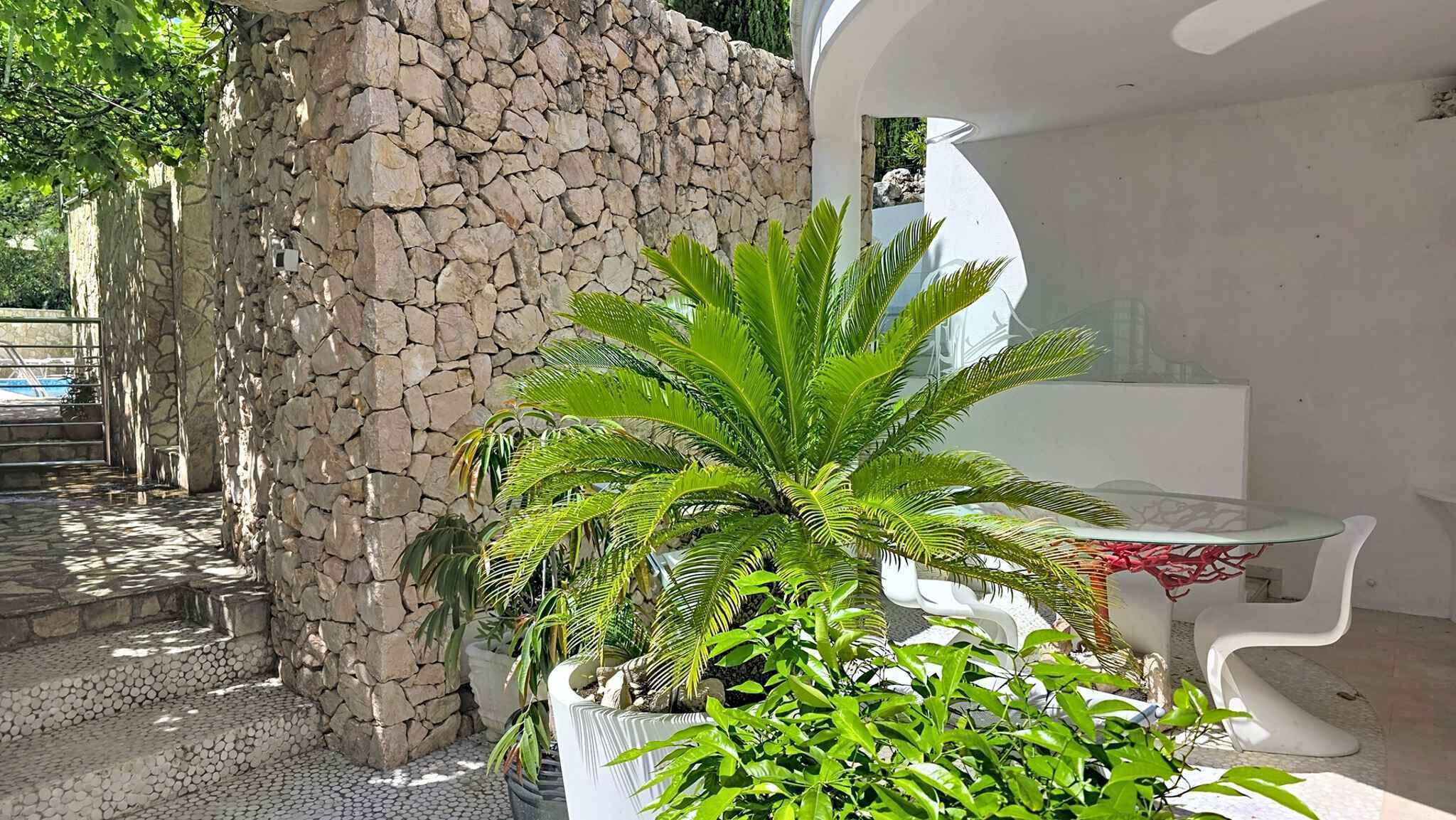 A stone wall, a white outdoor seating area, and potted plants.