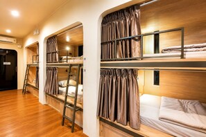 A room with bunk beds, wooden flooring, and curtains. - Phraya Hostel (Bangkok)