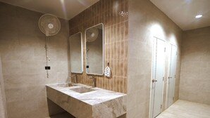 A modern bathroom with a large sink, two mirrors, a wall-mounted fan, and a door.