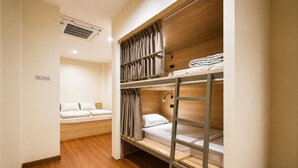 A bunk bed room with a single bed and a small seating area.