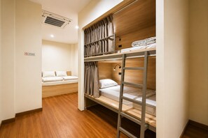 A bunk bed room with a single bed and a small seating area.