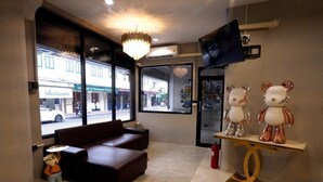 A hotel lobby with a sofa, a bear sculpture, and a TV on the wall.