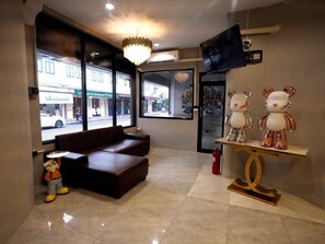 A hotel lobby with a sofa, a bear sculpture, and a TV on the wall.