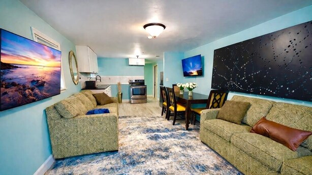A living room with a sofa, a coffee table, and a dining area with chairs and a table.