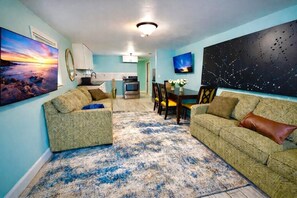A living room with a sofa, a coffee table, and a dining area with chairs and a table. - Glow Hard or Go Home - 12 mins to Downtown (Jacksonville)