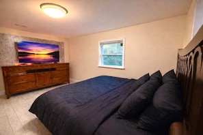 Ein Schlafzimmer mit einem Bett, einem Schminktisch, einem Gemälde und einem Fenster.