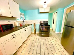A kitchen with white cabinets, a stainless steel refrigerator, a microwave, and an oven. - Glow Hard or Go Home - 12 mins to Downtown (Jacksonville)