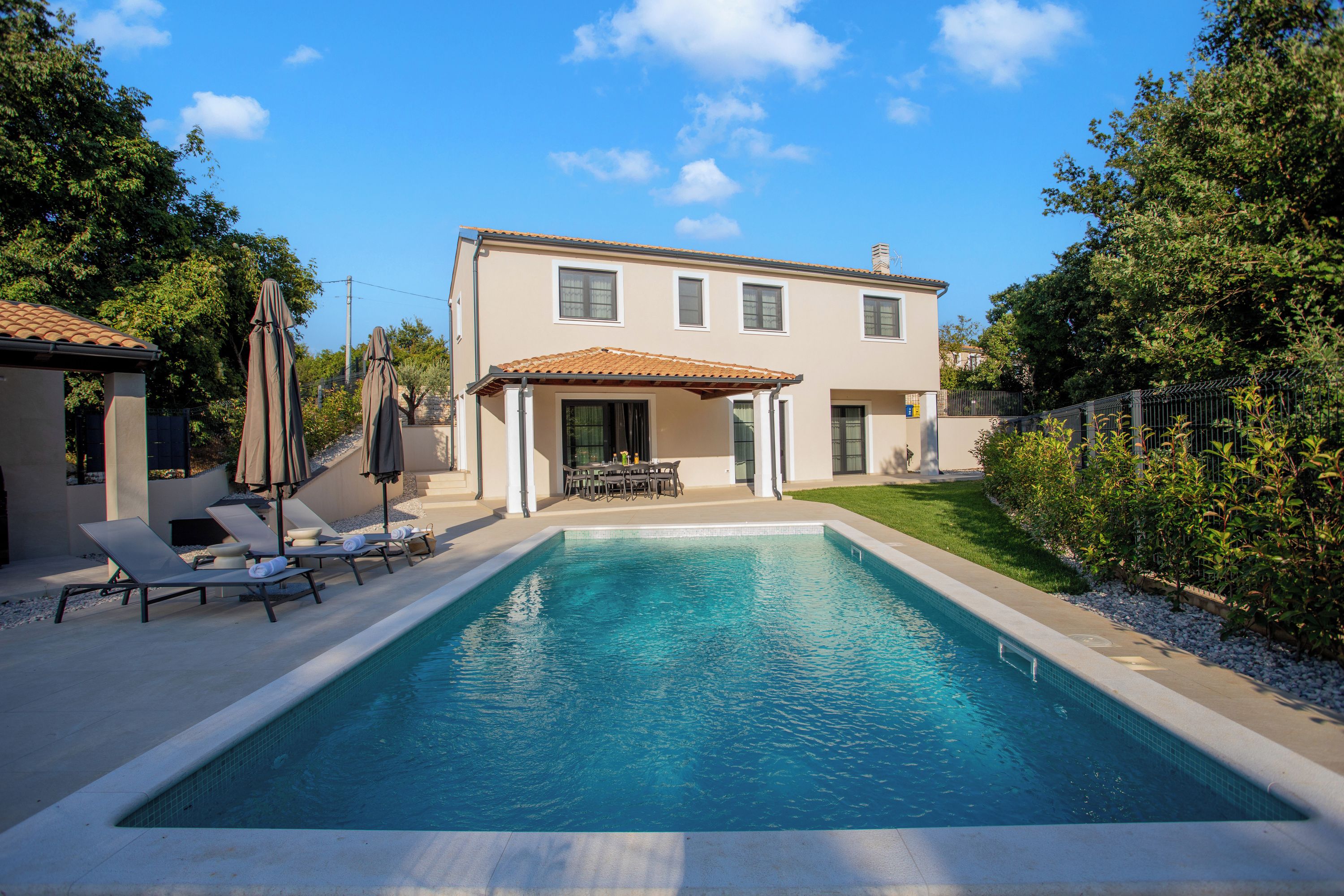 A two-story house with a swimming pool, outdoor seating, and a garden.