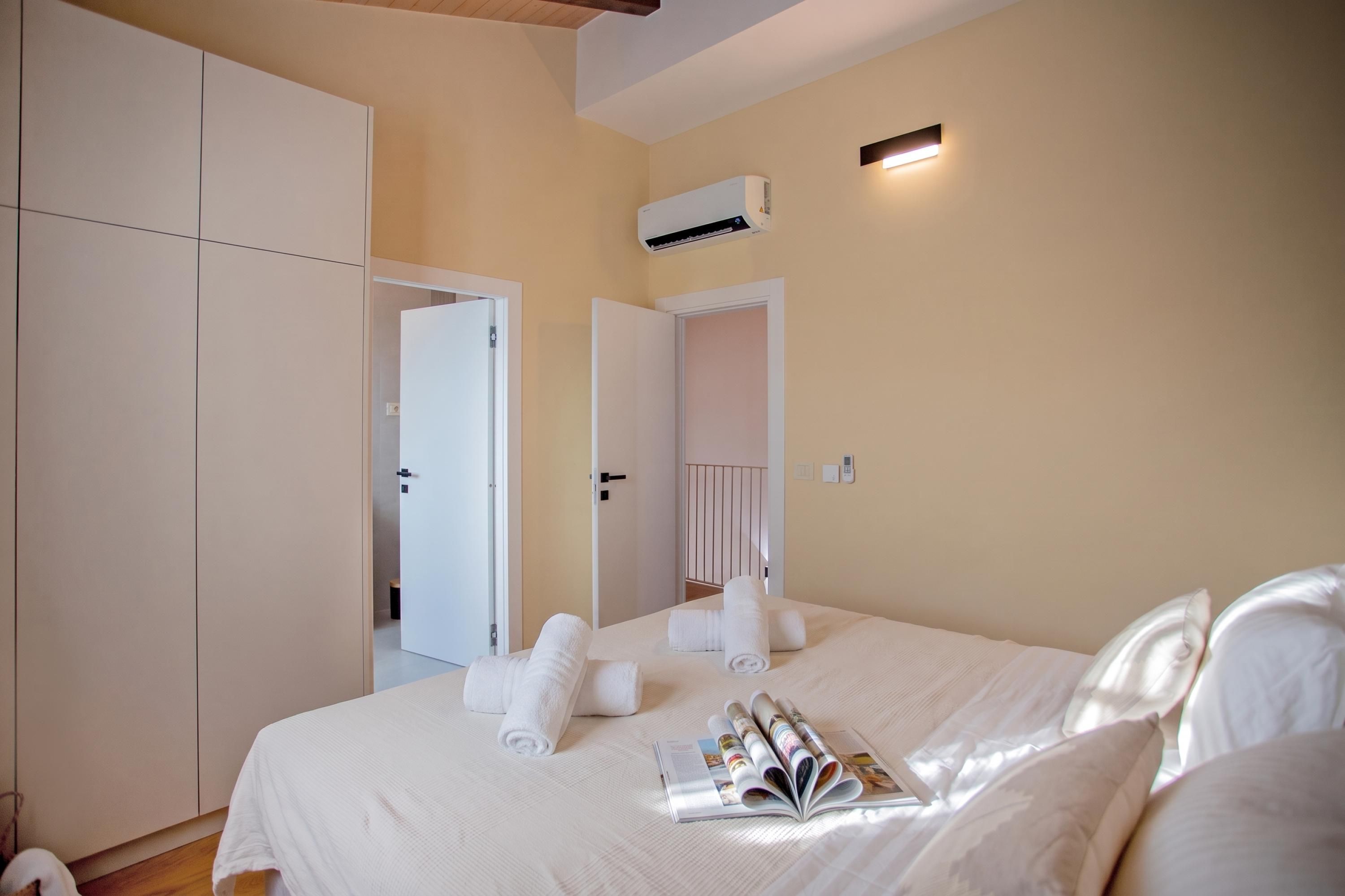 Habitación de hotel con cama, armario, aire acondicionado y puerta que da a otra habitación.