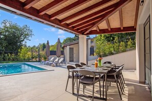Eine Außenpatio mit Pool, Liegestühlen und einem Esstisch.